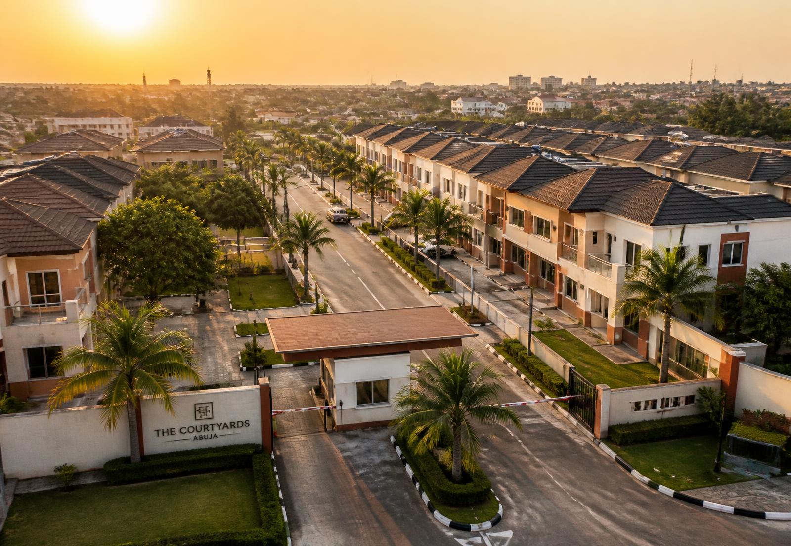 Aerial view of a gated residential estate at sunset with palm-lined streets and a gatehouse